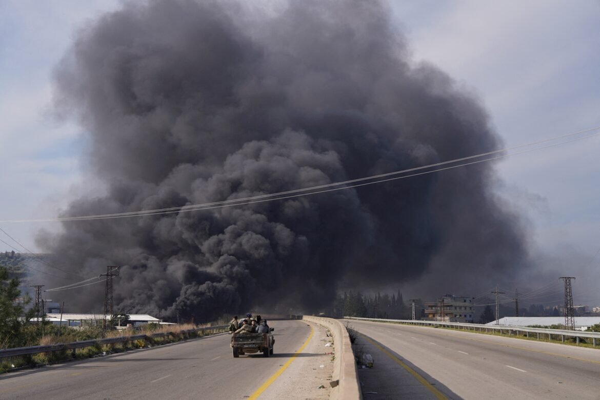 Hundreds of civilians informed murdered in massacres as violence in Photo: The smoke rises while the members of the Syrian forces travel in a vehicle in Latakia